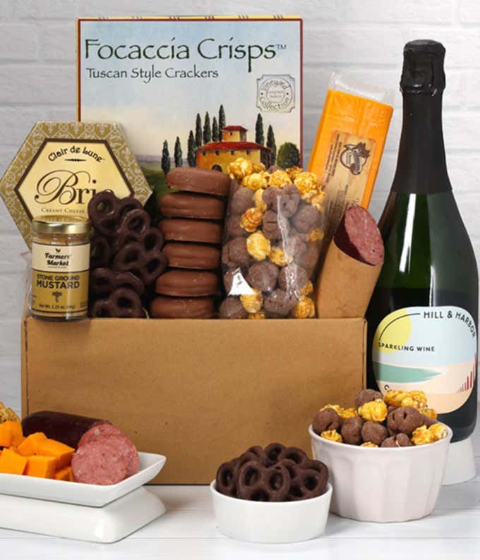 A gift set featuring a bottle of Hill & Harbor Sparkling Wine, focaccia crisps, 2 cheeses, mustard, summer sausage, caramel popcorn, chocolate pretzels, and 6 chocolate-covered Oreos for a sweet and savory gourmet experience.