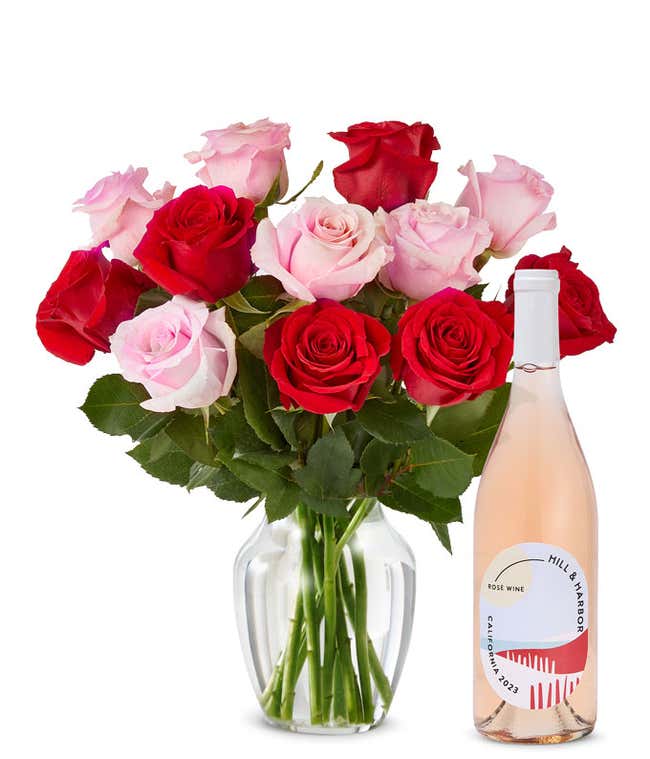A mix bouquet of one dozen red and blush roses fills a clear glass vase and is paired with a bottle of Hill &amp; Harbor California Ros&eacute;.