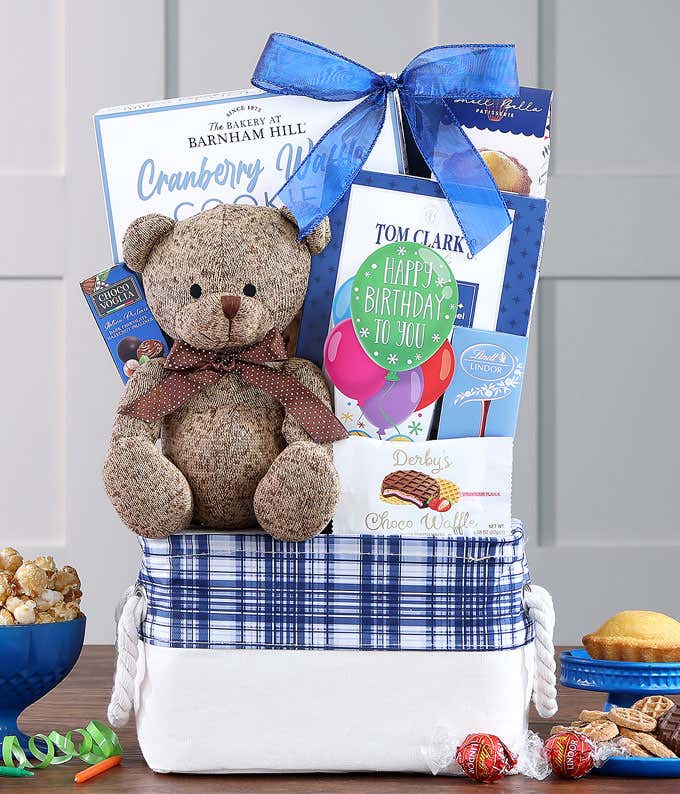 A canvas tote overfilled with snacks including birthday packaging and a brown bear.