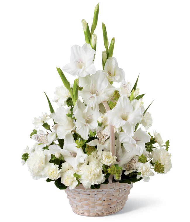 White basket arrangement with white gladiolus, white carnations, white alstroemeria, and greenery, styled in a fan shape with tall blooms rising in the center.