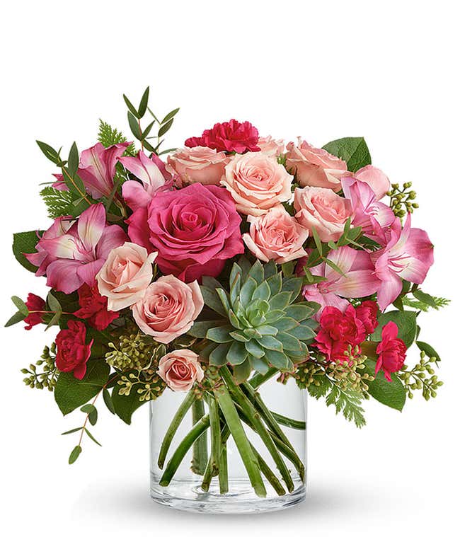 A vibrant floral arrangement featuring pink mini roses, pink alstroemeria, pink mini carnations, a succulent plant, and hot pink roses in deluxe and premium versions.