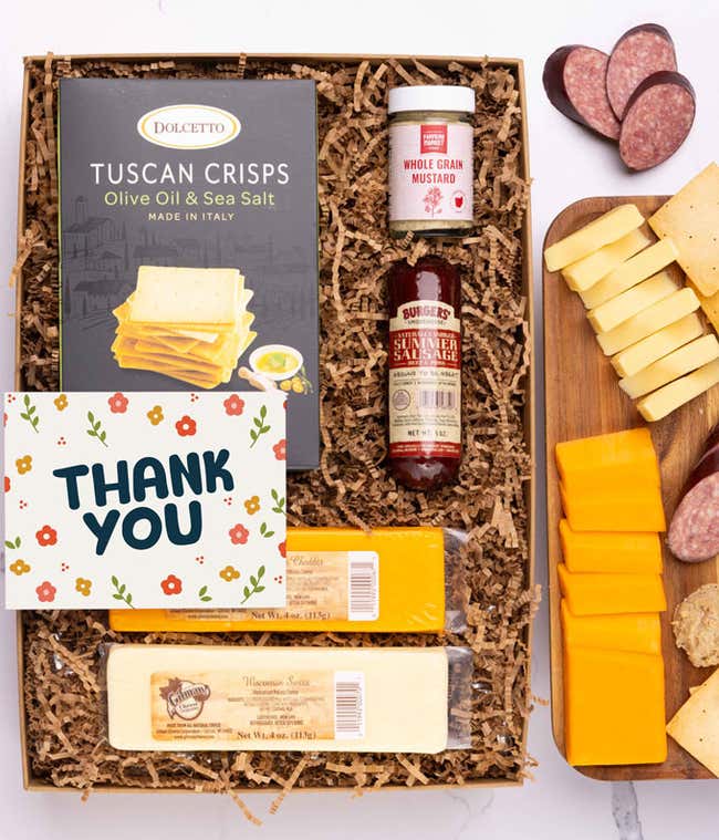 A charcuterie box with two types of cheese, crackers, stone-ground mustard, a summer sausage and a Thank You message card.
