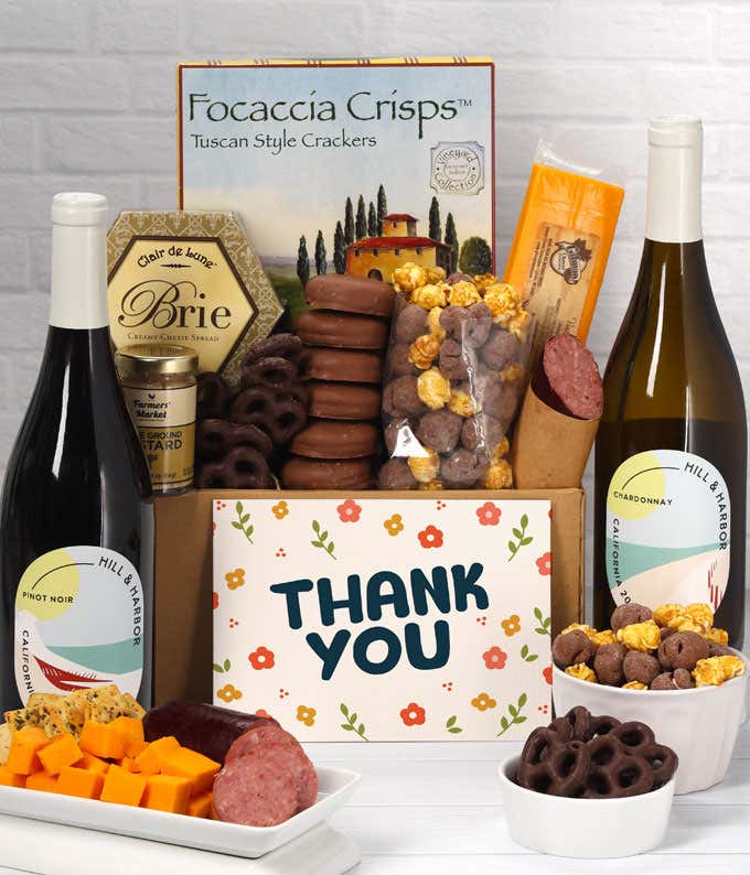 A gift set featuring two bottles of Hill & Harbor wine - white and red, focaccia crisps, two cheeses, mustard, summer sausage, caramel popcorn, chocolate pretzels, six chocolate-covered Oreos and a Thank You card to complete the gourmet experience.