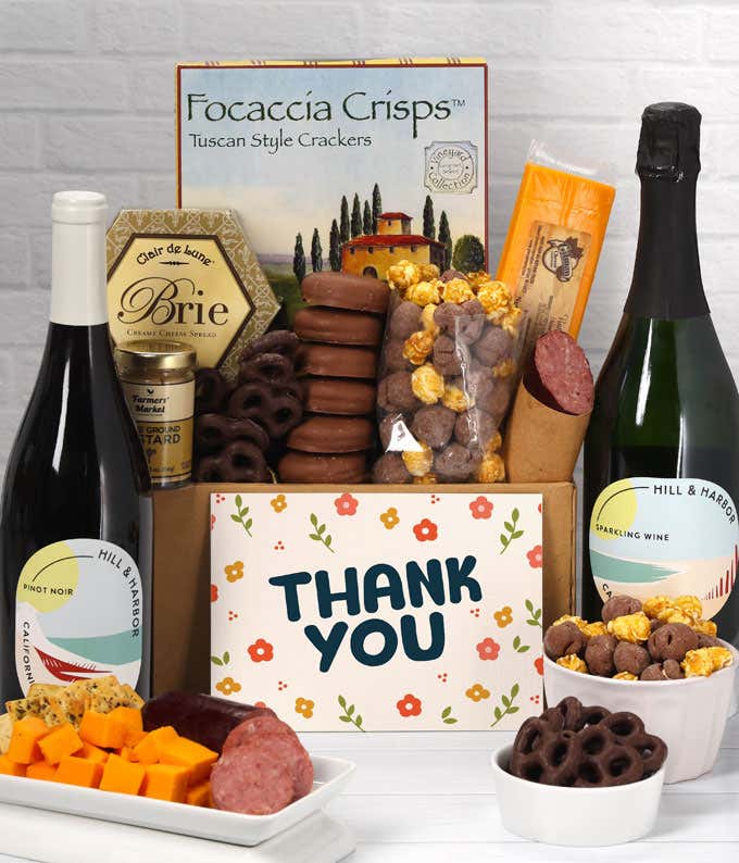 A gift set featuring 2 bottles of Hill & Harbor wine - red and sparkling, focaccia crisps, two cheeses, mustard, summer sausage, caramel popcorn, chocolate pretzels, six chocolate-covered Oreos and a Thank You card to complete the gourmet experience.