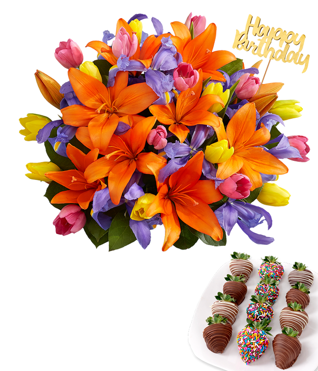 Partial image of Deluxe bouquet of orange lilies, purple irises, and multicolored tulips in a clear glass vase with a gold Happy Birthday pick, paired with a plate of swizzled and rainbow sprinkle chocolate-covered strawberries. without vase.